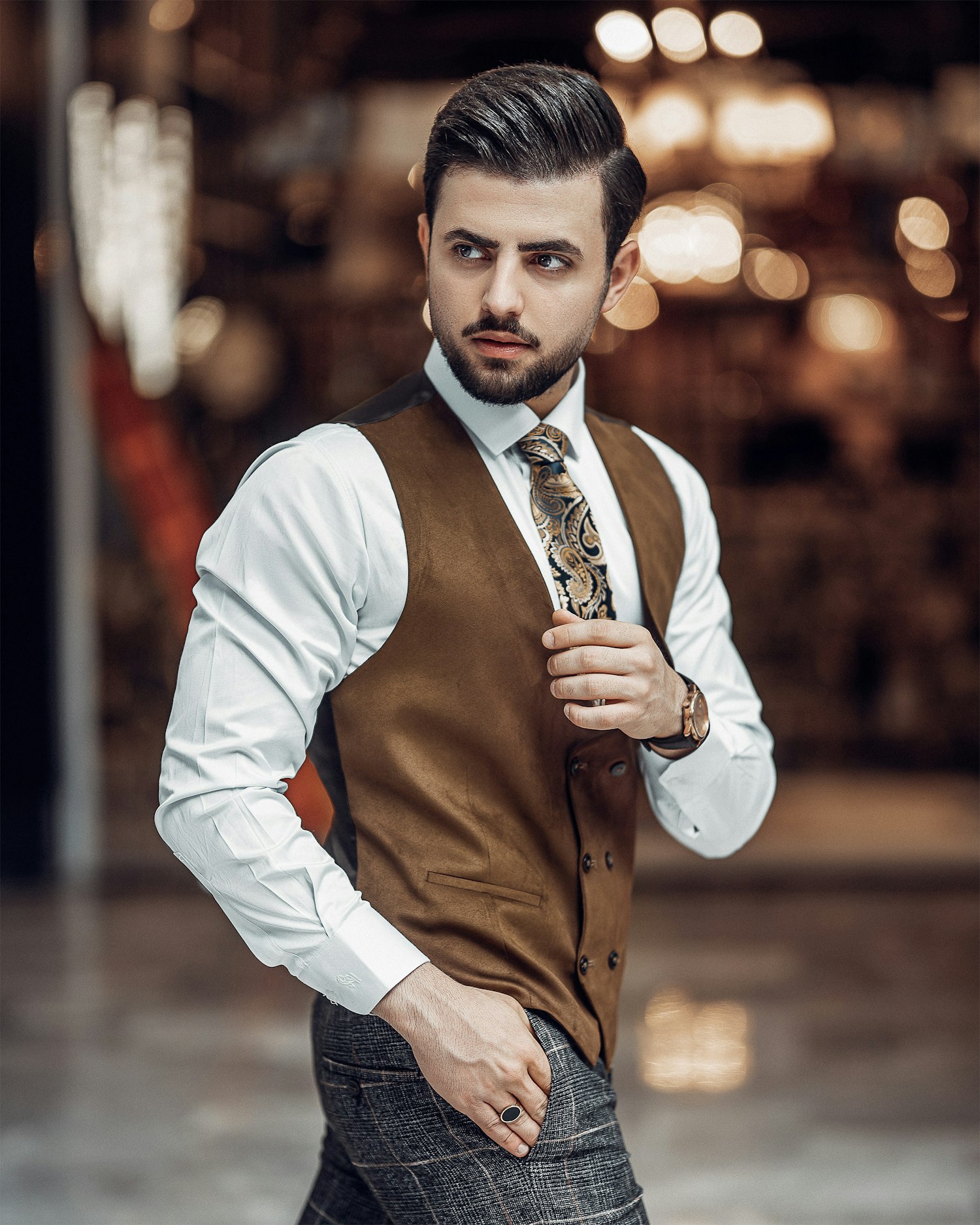Client in a tan waistcoat and paisley tie standing in warm light