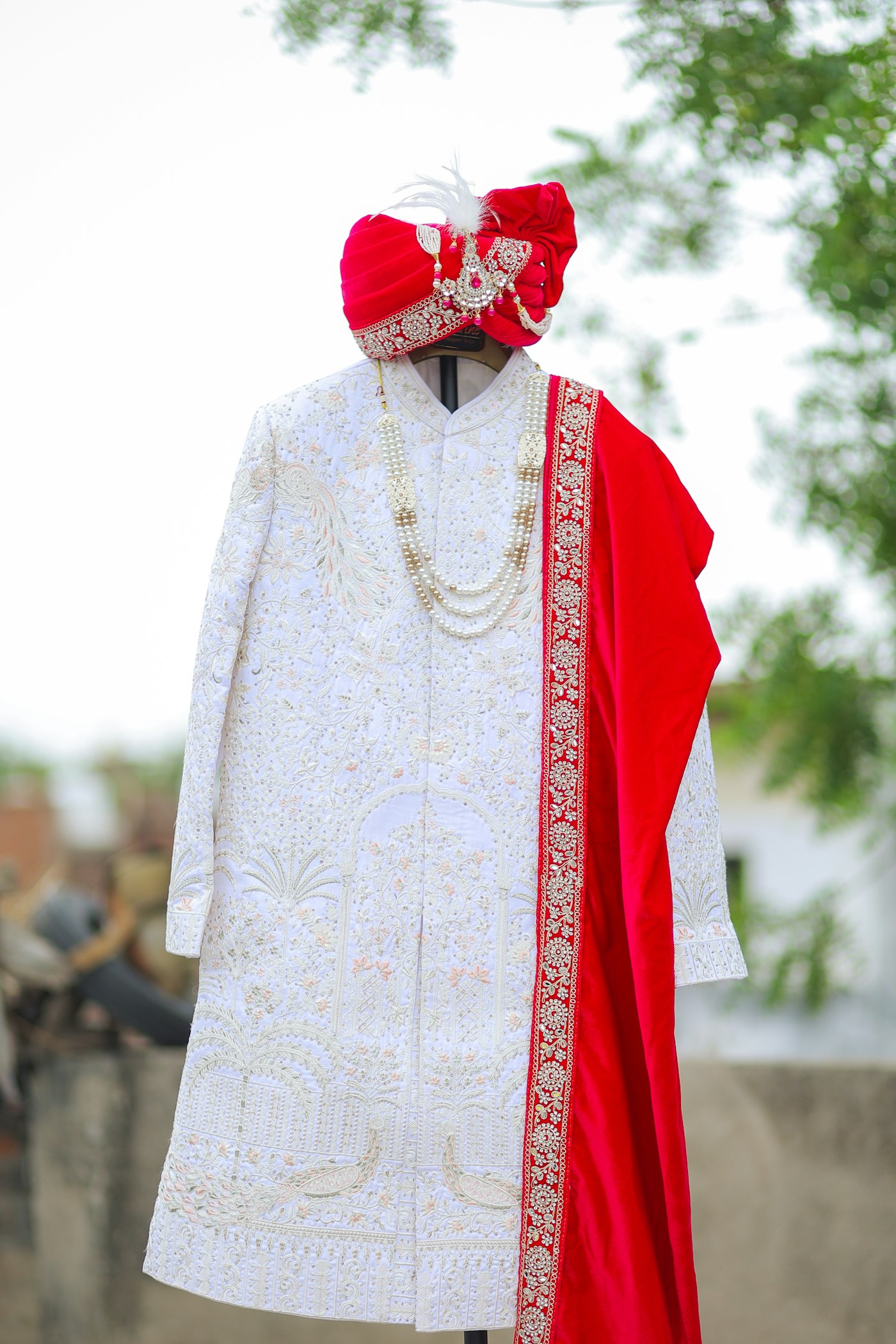 Ivory hand-embroidered sherwani with pearl haar and crimson safa on a dress stand
