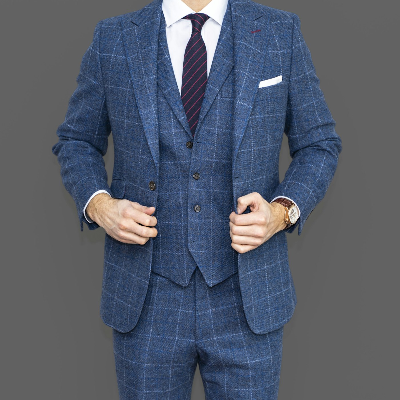 Bespoke blue windowpane three-piece suit, jacket held open at the lapels