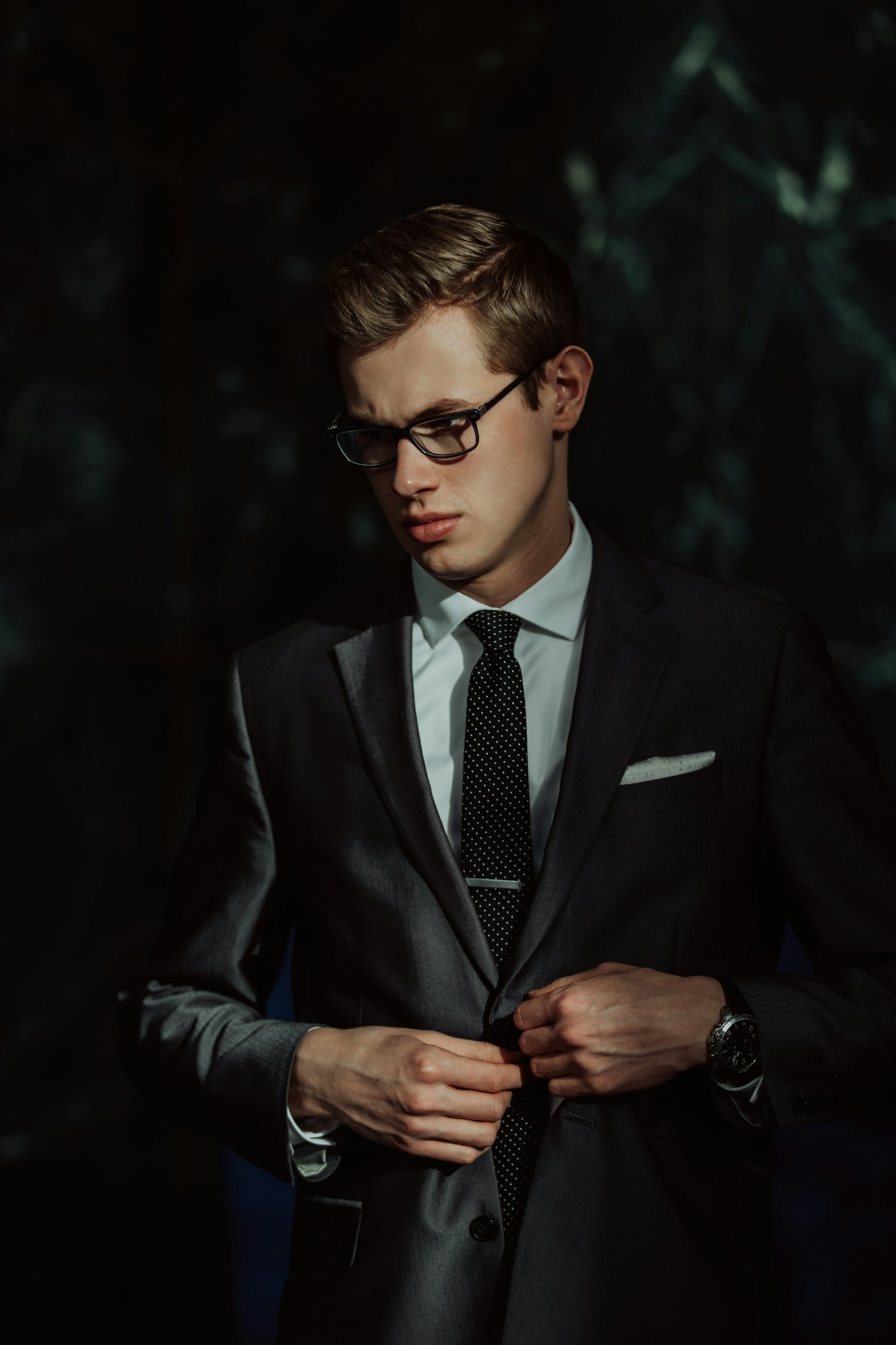 Charcoal suit with a crisp white shirt and tie, jacket being buttoned